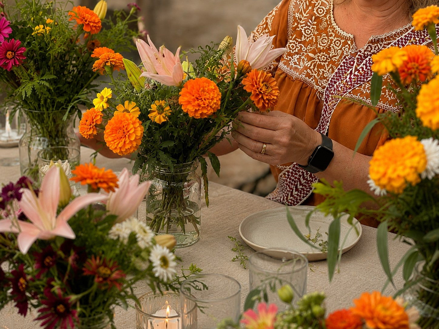 Arranging locally grown seasonal flowers from Bella Vista Flower Farm into simple table arrangements for hosting friends.